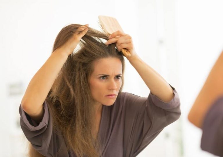 Une jeune femme qui découvre ses nouveaux cheveux blancs dans le miroir de sa salle de bain.