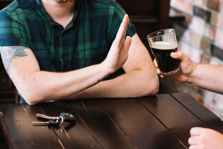 Un jeune homme refuse le verre d'alcool qui lui est proposé.