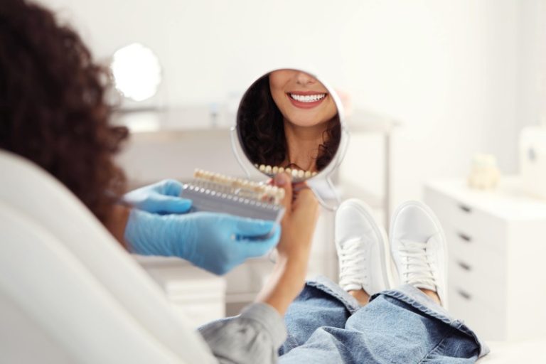 Une femme chez le dentiste regardant les résultats de son blanchiment dentaire dans un miroir.