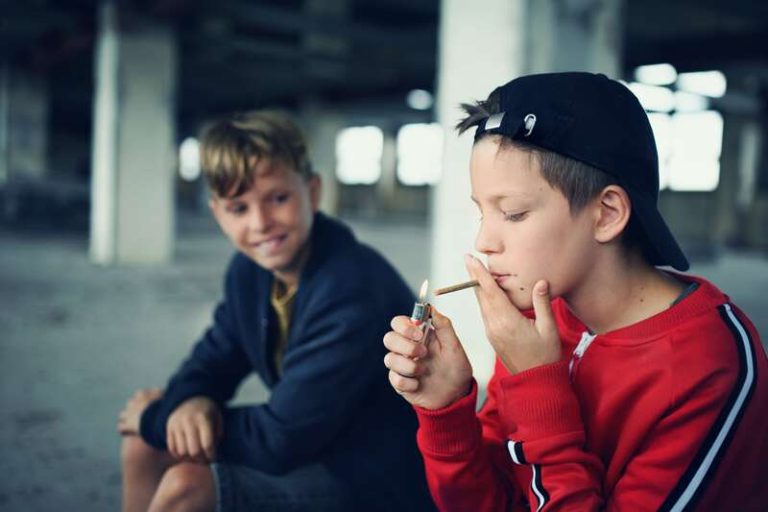 Un jeune adolescent, inconscient des risques du tabac, en train d'allumer une cigarette.