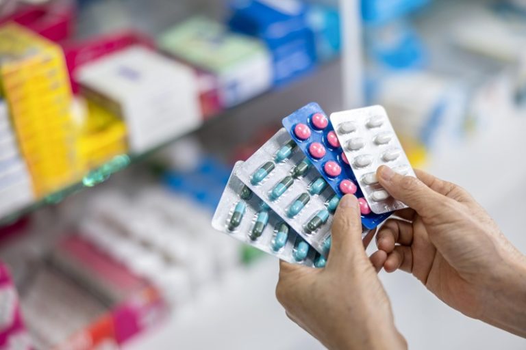 Une pharmacienne qui tient différents types d'anti-inflammatoires dans ses mains.