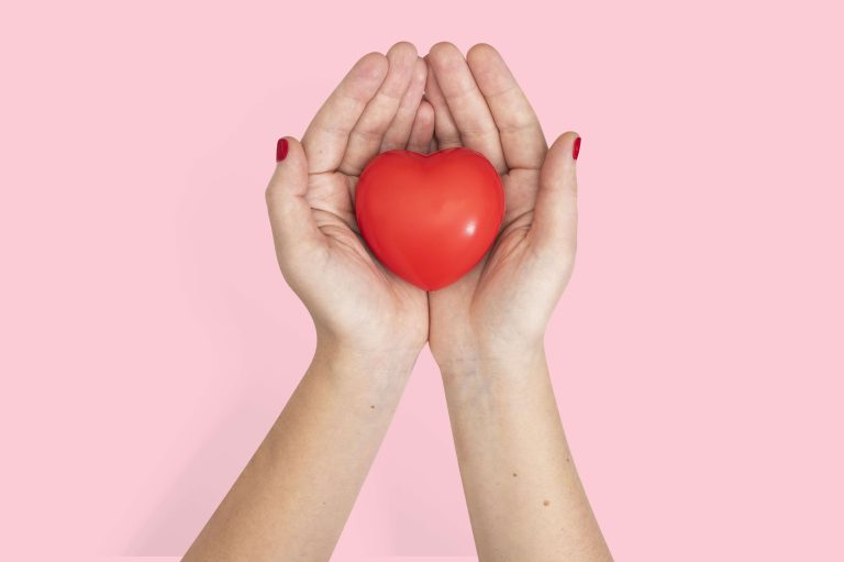 Deux mains ouvertes tiennent un cœur rouge dont il faut prendre soin.