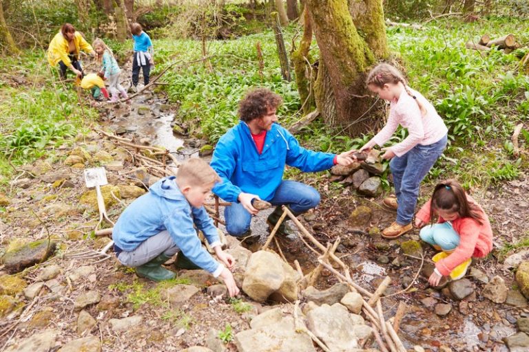 Une famille avec des enfants qui joue dans la nature, au contact de la terre.