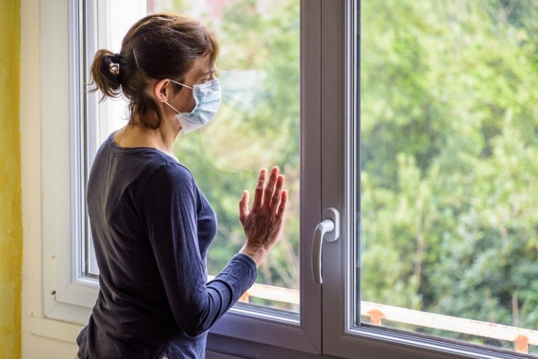 Une femme confinée qui regarde par la fenêtre pour se changer les idées.
