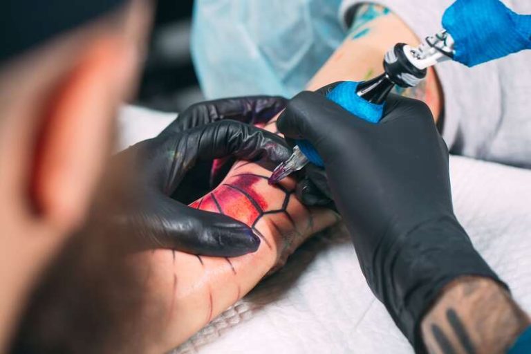 Un tatoueur est en train de tatouer le bras d'une femme avec des encres industrielles.