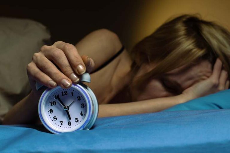 Une femme dans son lit qui vient de se réveiller et qui est déjà fatiguée.