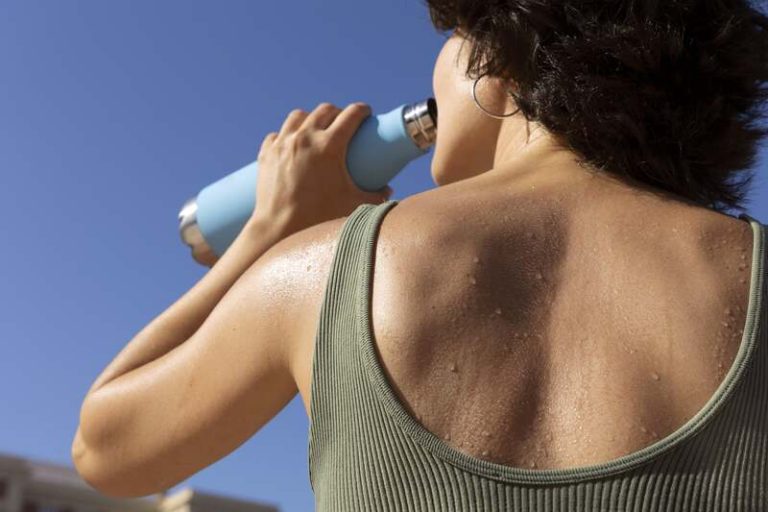 Une femme qui s'hydrate en période de canicule pour éviter l'insuffisance rénale.