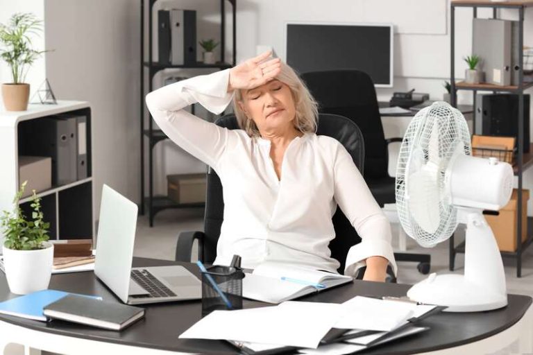 Une femme au travail souffrant de symptômes liés à la ménopause.