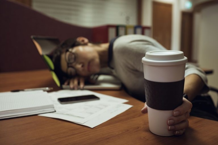 Une femme qui dort au travail à cause de sa dette de sommeil.