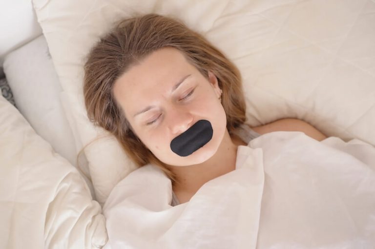 Une jeune femme dormant avec un ruban sur la bouche.
