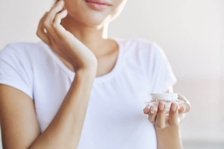 Une femme utilisant de la crème hydratante pour contrer la peau sèche.