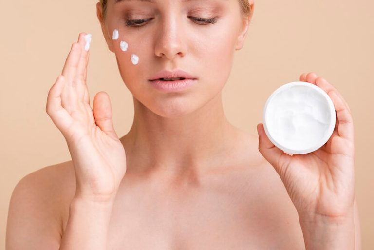 Une jeune femme étalant de la crème pour traiter son eczéma.