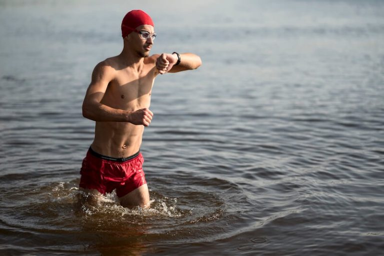 Homme qui marche dans l'eau en regardant sa montre.