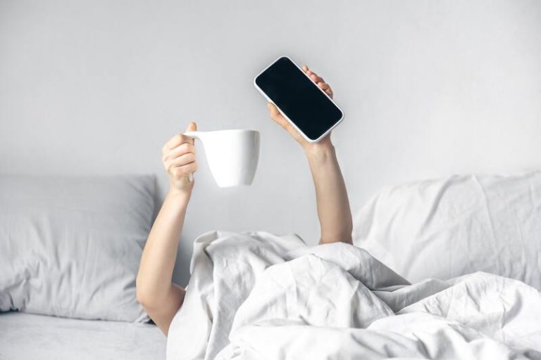 Un homme qui se réveille fatigué, smartphone en main.