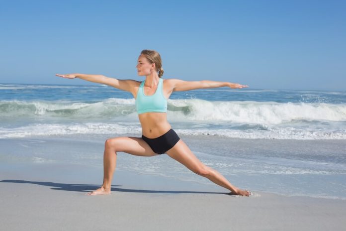 Femme sport plage activite physique ete ma sante Une jeune femme faisant des étirements sur le sable, face à la mer.