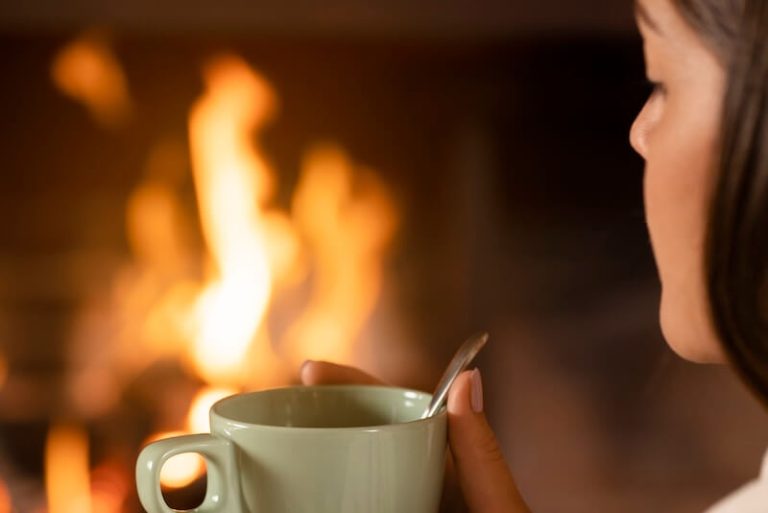 Une jeune femme buvant une tasse de café trop chaud.