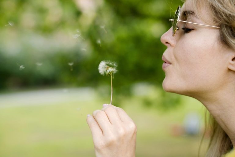 Une femme qui souffle sur une fleur sans être consciente que son souffle peut un jour devenir un moyen de la reconnaître précisément.
