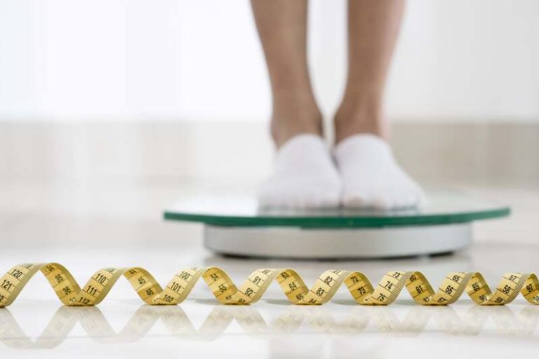Une femme sur une balance qui prend des médicaments pour perdre du poids.