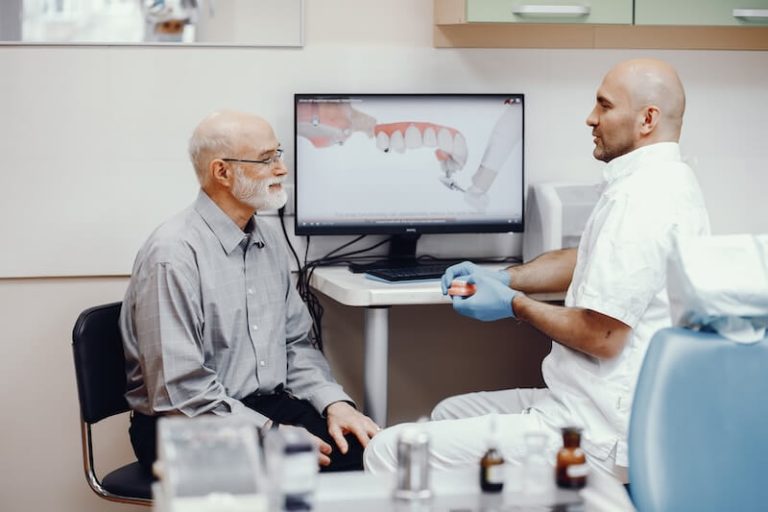 Un dentiste explique à son patient les différents types de prothèses dentaires.