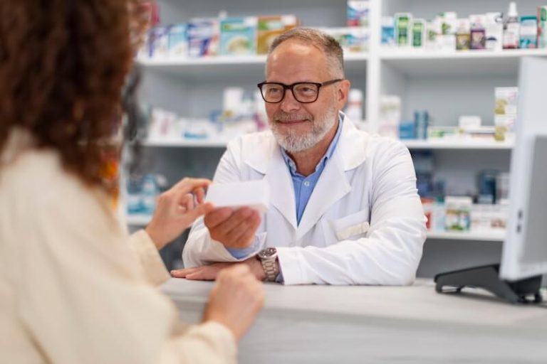 Un pharmacien présentant un médicament à un patient, soumis au doublement de la franchise médicale.
