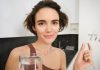 Une jeune femme consomme un complément alimentaire d'origine végétarienne.