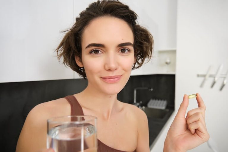 Une jeune femme consomme un complément alimentaire d'origine végétarienne.