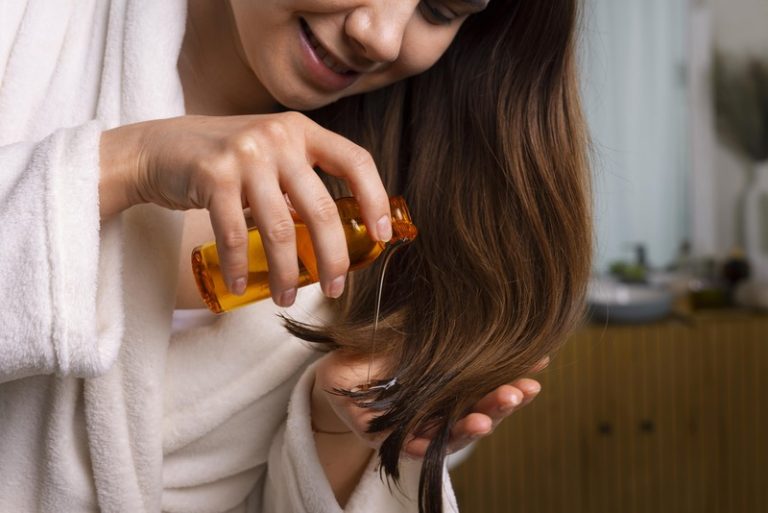 Une femme qui utilise de l'huile de coco pour réparer ses cheveux abîmés.