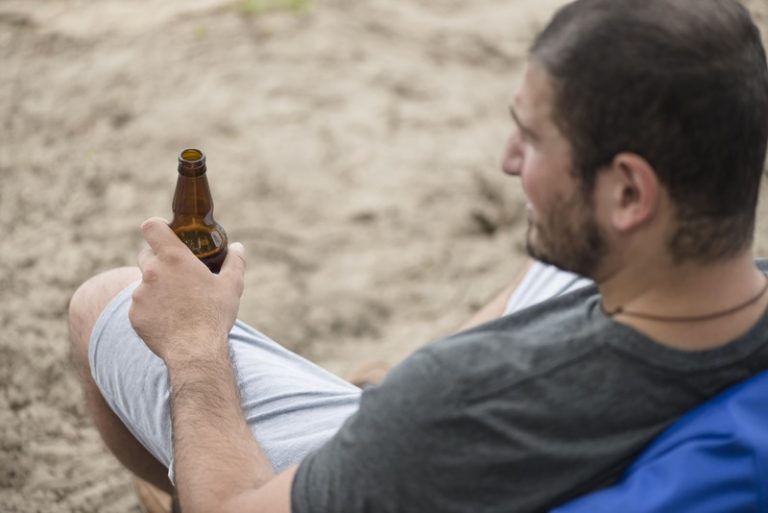 Un homme qui boit une bière après avoir fini son sport.
