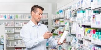 Un homme qui scanne une boîte de médicaments pour accéder à la notice explicative.