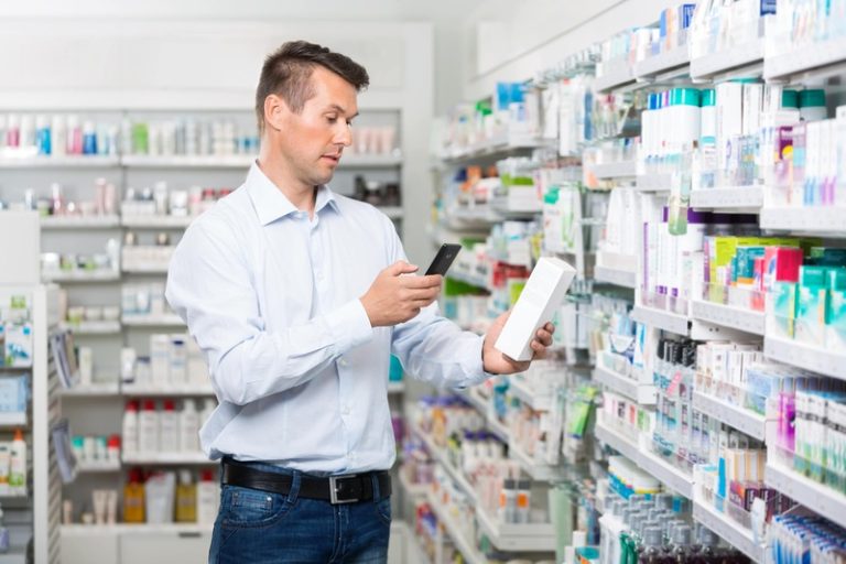 Un homme qui scanne une boîte de médicaments pour accéder à la notice explicative.