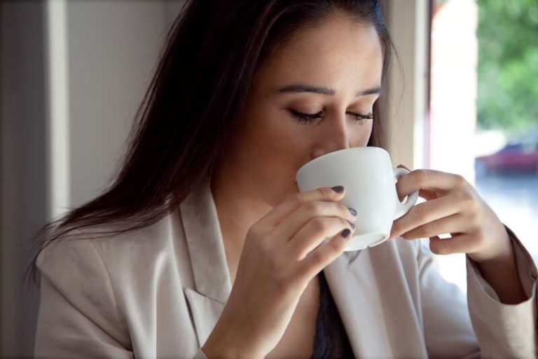 Une femme heureuse qui boit un café tous les matins pour être de bonne humeur.