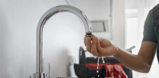 Carafes filtrantes, filtres sur robinet : sont-ils efficaces contre les polluants ? Un homme qui installe un filtre à eau sur son robinet.