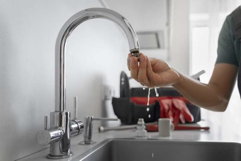 Un homme qui installe un filtre à eau sur son robinet.