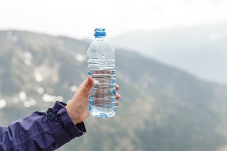 Une femme qui tient une bouteille en plastique avec de l'eau qui est restée longtemps dedans.