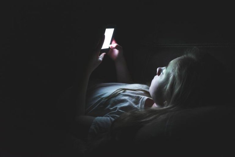 Une jeune adoslescente interné en hôpital psychiatrique qui regarde son téléphone.