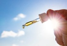 Une main devant le soleil avec des gouttes pour une cure de vitamine D.