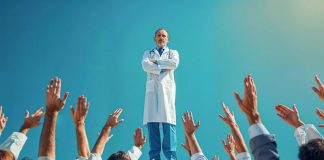 Déserts médicaux : les missions de solidarité territoriale sont-elles une solution ? Un médecin sur un podium entouré par plein de gens qui demandent un rendez- vous pour illustrer la pénurie de médecins et les déserts médicaux