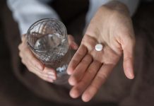 Une femme qui tient de l'aspirine dans sa main, croyant que ça peut réduire son risque de cancer colorectal.