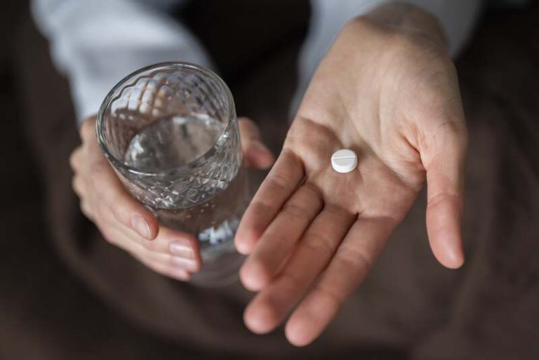 Une femme qui tient de l'aspirine dans sa main, croyant que ça peut réduire son risque de cancer colorectal.