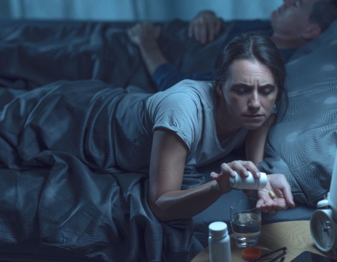 somnifères benzodiazépines efficacité risques sommeil santé cérébrale cerveau Ma Santé Une femme qui prend des somnifères pour pouvoir vaincre son insomnie et essayer de dormir.