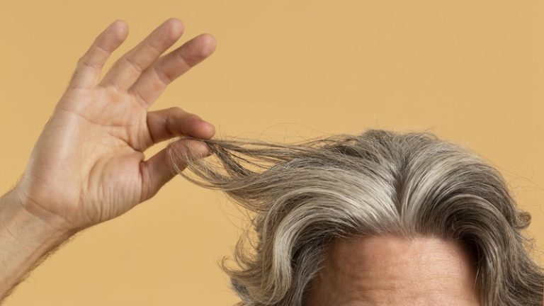 Un homme qui montre ses cheveux gris, signe de défense contre le cancer.