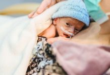 Un bébé prématuré qui fait du peau à peau dans les bras de sa mère.