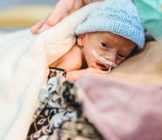 Un bébé prématuré qui fait du peau à peau dans les bras de sa mère.