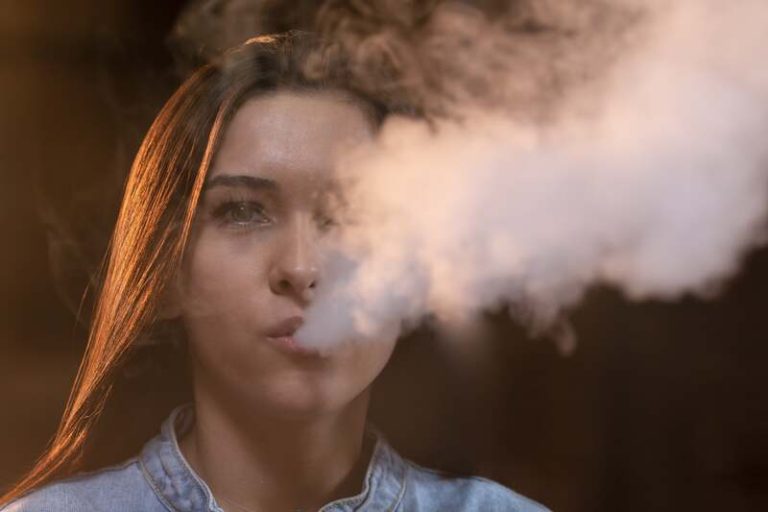 Une femme qui essaye d'arrêter de fumer en utilisant une cigarette électronique pour réduire peu à peu sa dépendance à la nicotine.