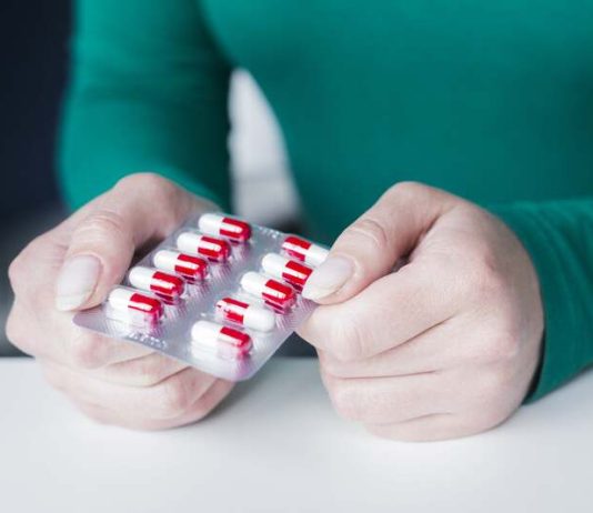 Une femme qui tient des médicaments dans ses mains après avoir compris qu'ils laisseraient des traces dans son microbiote.