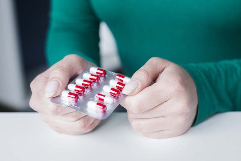 Une femme qui tient des médicaments dans ses mains après avoir compris qu'ils laisseraient des traces dans son microbiote.