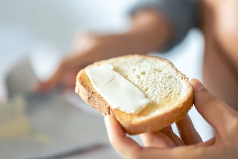 Une femme qui beurre sa tartine de beurre salé.