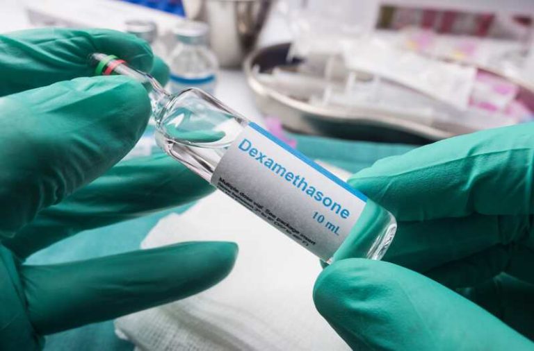 Un médecin qui tient dans ses mains gantées le médicament du covid qui protège les vaisseaux sanguins, la dexaméthasone.