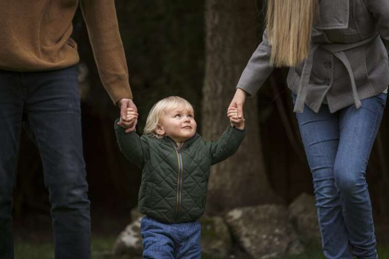 Un enfant qui tient la main de chacuns de ses deux parents.