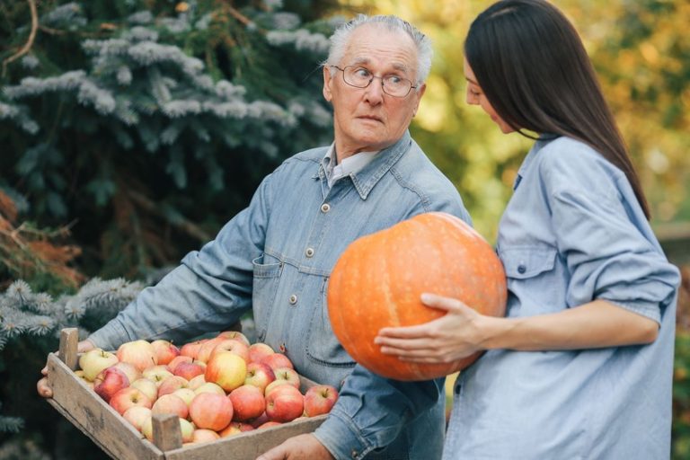 Un grand père et s petite fille en train d'acheter des fruits et légumes de saison d'automne en circuit court.
